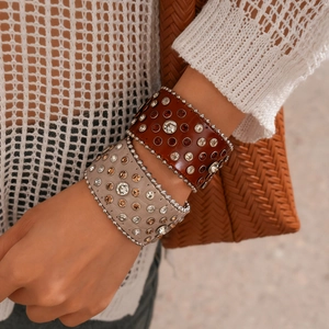 Détail de bracelets punk en cuir avec strass en marron foncé et abricot clair