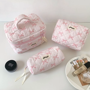Three-piece set of pink quilted bow cosmetic bags in various sizes with handle and zip closure