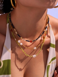 Detail of beaded necklace with lapis lazuli, red agate, and freshwater pearls on model