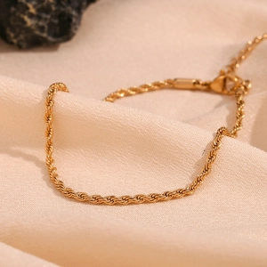 Close-up of 18K gold plated 2mm twist rope chain with lobster clasp on beige fabric