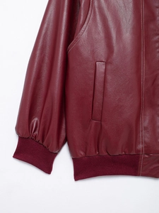 Detail view of burgundy leather jacket featuring ribbed cuffs and side pocket stitching