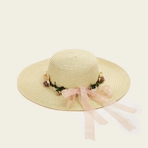 Detail of beige straw sun hat with decorative dark roses and pink chiffon ribbon