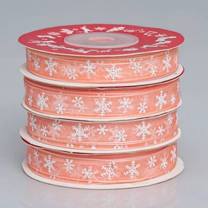 Close-up of four stacked semi-transparent orange-pink Christmas ribbons with snowflake prints