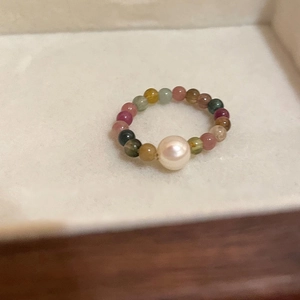 Close-up of handmade beaded ring with colorful tourmaline stones and central white pearl