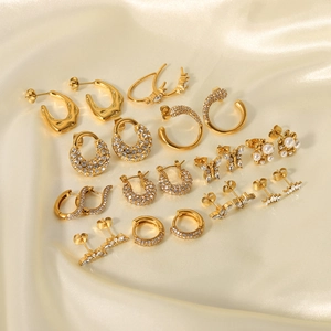 Boucles d'oreilles dorées en papillon zircon et perles sur fond de soie dorée brillante