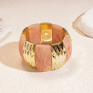 Detailed shot of pink marble resin and hammered gold alloy stretch bracelet textures