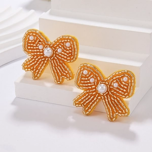 Detail of yellow bow beaded earrings with gold glass beads and white imitation pearls