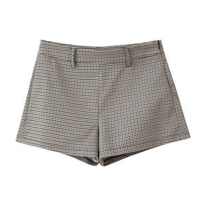 Detail of high-waisted houndstooth plaid shorts with fine woven texture on white background