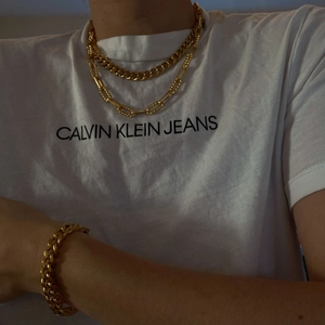 Macro detail of stacked gold Cuban chain bracelets and layered necklaces on a model