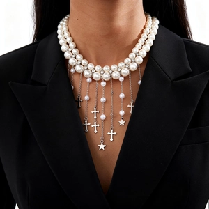 Collier double couche en perles avec pendentifs étoiles et croix sur veste de costume