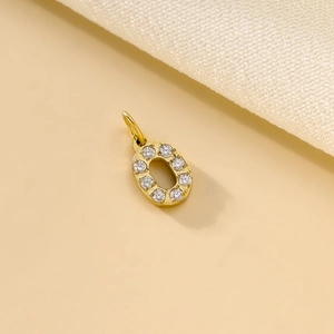 Detailed close-up of a gold letter O pendant with sparkling diamond inlay on fabric