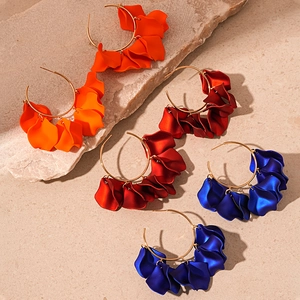 Vintage acrylic petal hoop earrings in orange, dark red and blue on stone texture