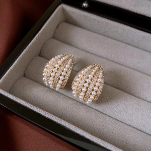 Macro shot of gold-plated U-shaped earrings with pearls and zircon in a velvet jewelry box