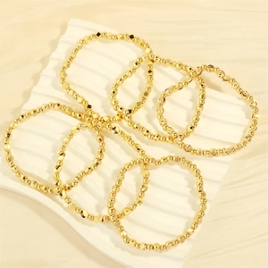 Detailed view of assorted gold beaded stretch bracelets with geometric textured metal beads