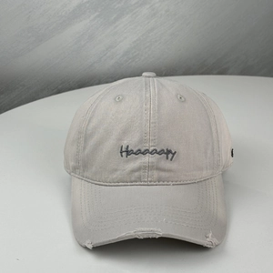Close-up of embroidered Haaaaapy text and distressed ripped brim on gray baseball cap