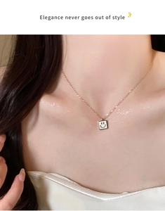 Rose gold smiley face necklace with white shell pendant worn on a model's collarbone