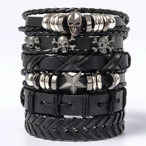 Stacked set of black leather bracelets with skull and star charms on white background