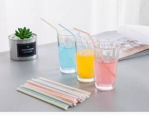 Close-up of disposable flexible plastic straws with colorful stripes in beverage glasses