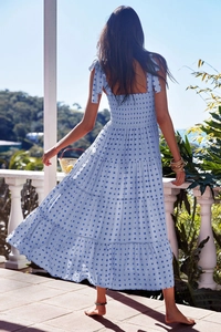 Detailed view of blue checkered dress featuring tiered skirt and shoulder tie straps