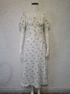 Detail of floral print pattern on white midi dress with puff sleeves and side slit