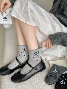 Close-up of Japanese style knit socks with black bow jacquard and ruffle trim details