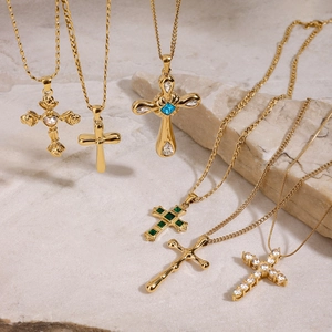 Collection de colliers croix en acier doré avec émeraudes et saphirs sur des pierres blanches