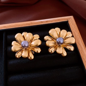 Macro detail of 18k gold plated flower earrings with a grey-purple pearl on black velvet