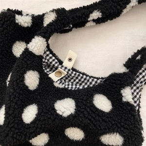 Détail du sac peluche à pois blancs, avec doublure à carreaux et bouton pression en métal