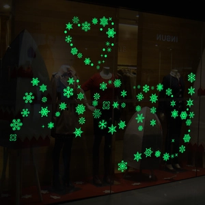 Luminous snowflake Christmas window stickers glowing green in heart-shaped arrangement