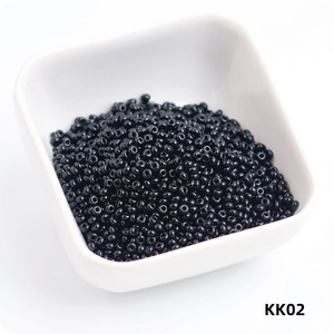 Close-up of 3mm black glass seed beads in a white container for DIY jewelry making