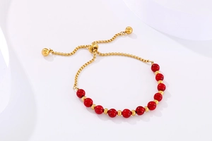 Détail d'un bracelet réglable en or avec des perles turquoise rouges sur soie blanche