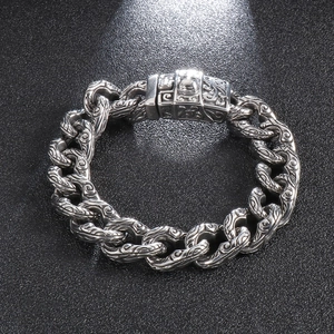 Close-up of a heavy silver stainless steel chain bracelet with detailed skull carvings