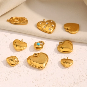 Macro view of gold-plated stainless steel heart charms with blue gems and floral relief