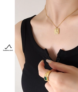 Detail of 18K gold plated stainless steel sun relief pendant necklace and emerald ring