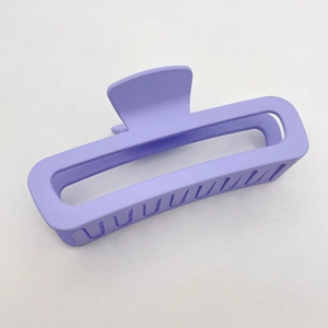 Macro detail of purple matte square claw clip with hollow design on grey fabric
