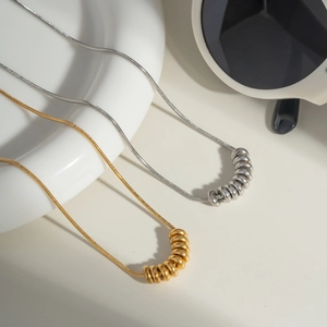 Detail shot of gold and silver snake chain necklaces with round pendant charms