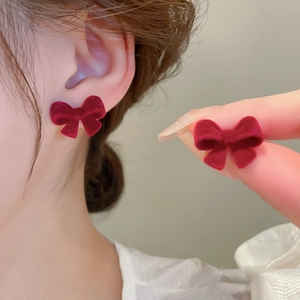 Dettaglio orecchini a fiocco rosso floccato con texture vellutata e design chic