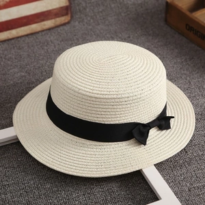 Top-down view of beige straw boater hat with black ribbon and fine woven texture detail
