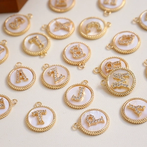 Close-up of gold-plated alphabet charms with white mother of pearl and zircon stones