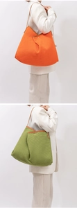 Detail of woven tote bags in orange and green with high-quality leather shoulder straps