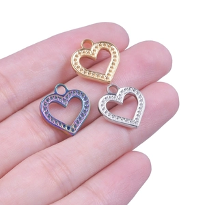 Close-up of heart-shaped steel pendants in gold, silver, and rainbow on a palm