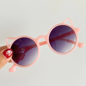 Detail view of pink cat-ear children's sunglasses with round tinted lenses