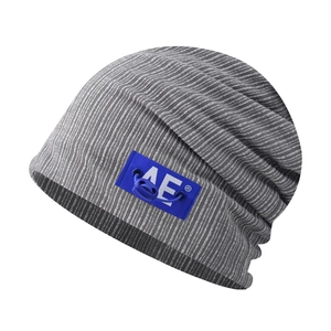 Macro detail of grey ribbed knit beanie with blue AE logo patch and drawstring element