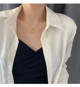 Detailed view of a gold crescent moon pendant with a sparkling diamond on a thin chain