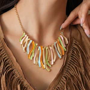 Détail d'un pendentif vague en émail coloré porté sur un vêtement en daim à franges