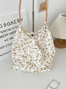 Detail of floral canvas tote bag featuring orange checkerboard straps and vintage brand label
