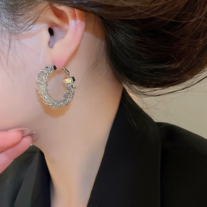 Close-up of silver hoop earrings with woven texture worn by model for daily style