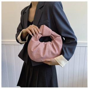 Detailed close-up of a pink sparkling fabric handbag with a stylish knotted top handle