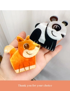 Detail of cute acrylic panda and fox hair clips held in hand with bright lighting