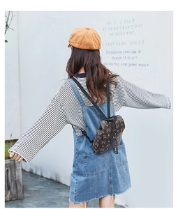 Rear view of model wearing a mini brown patterned backpack with flap and black straps